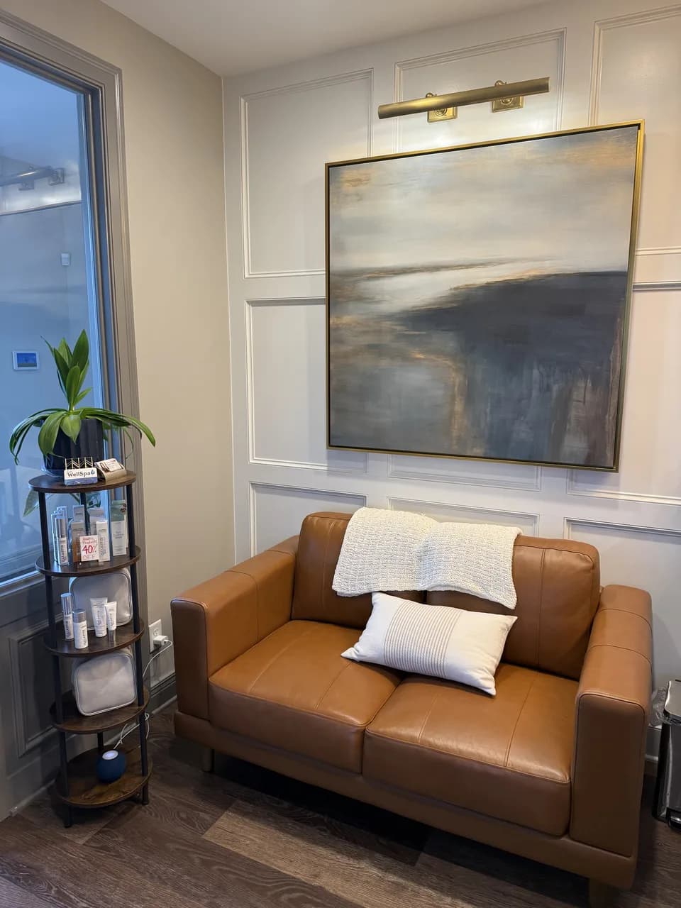 A leather loveseat beneath artwork in the LouWellSpa waiting area