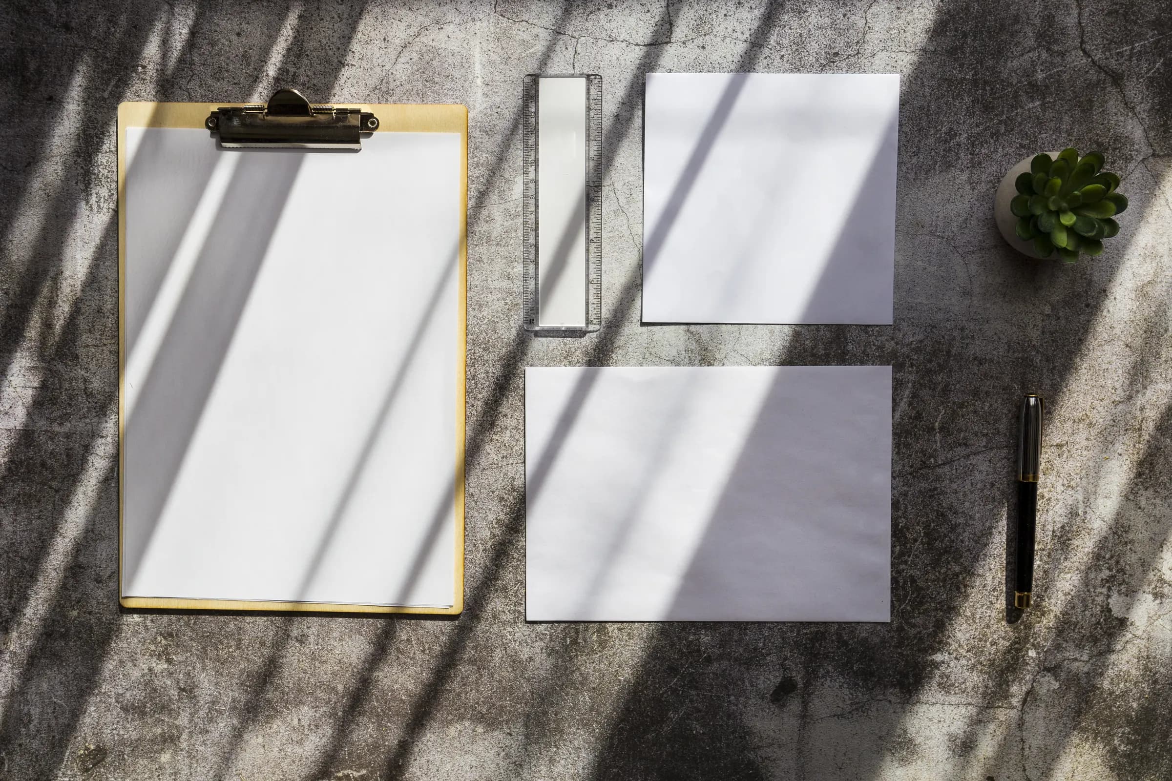 Clipboard and neutral paperwork arranged on a stone surface in window light